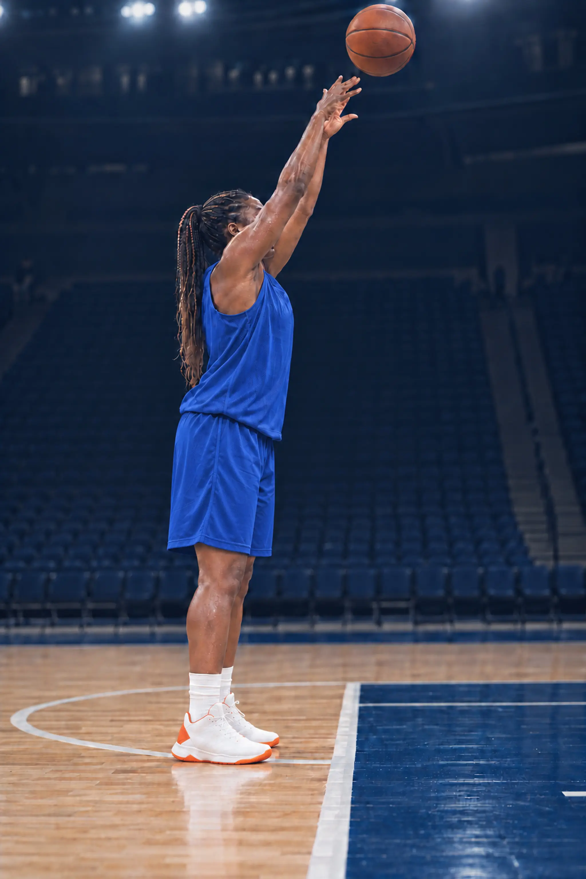 A basketball player at the free-throw line of an empty gym
