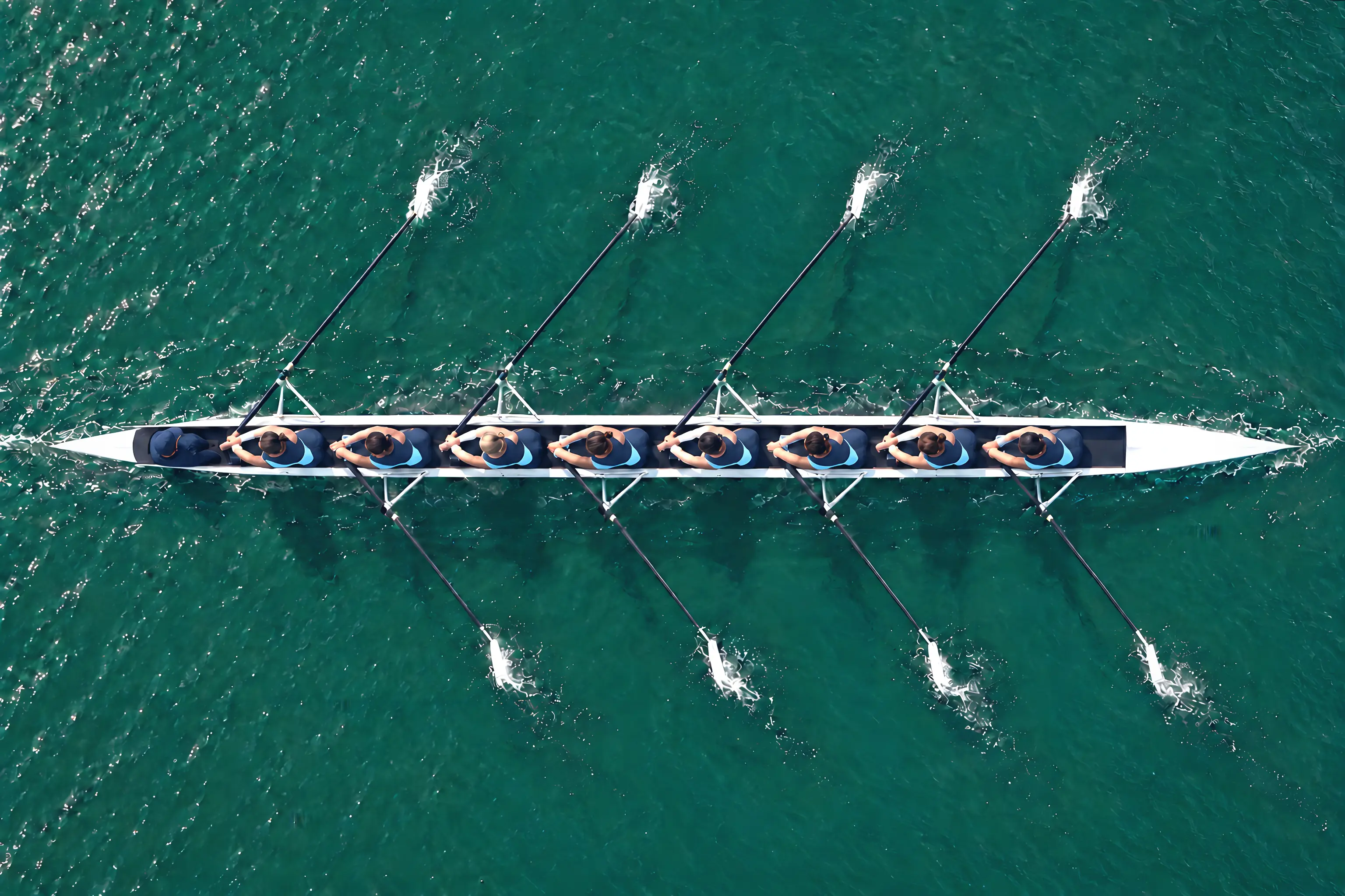 A rowing eight seen from above, blades level on the water